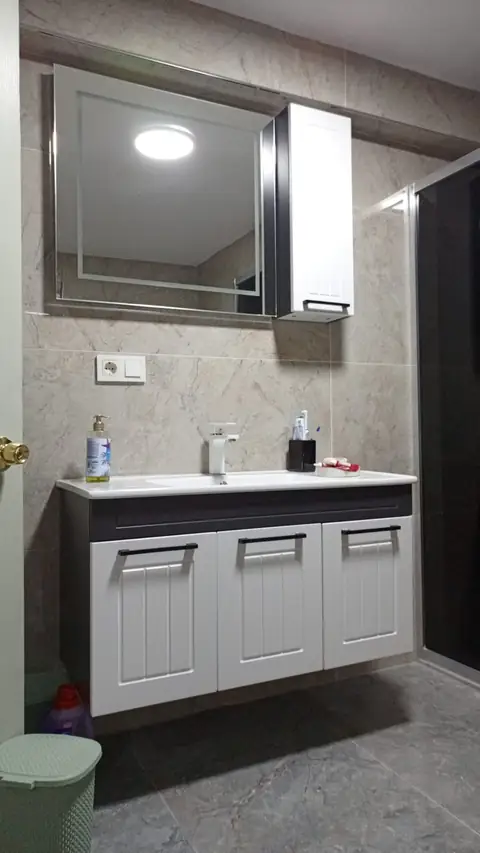 Mermer desenli duvar seramiği önünde asma lavabo dolabı ve aynalı dolap